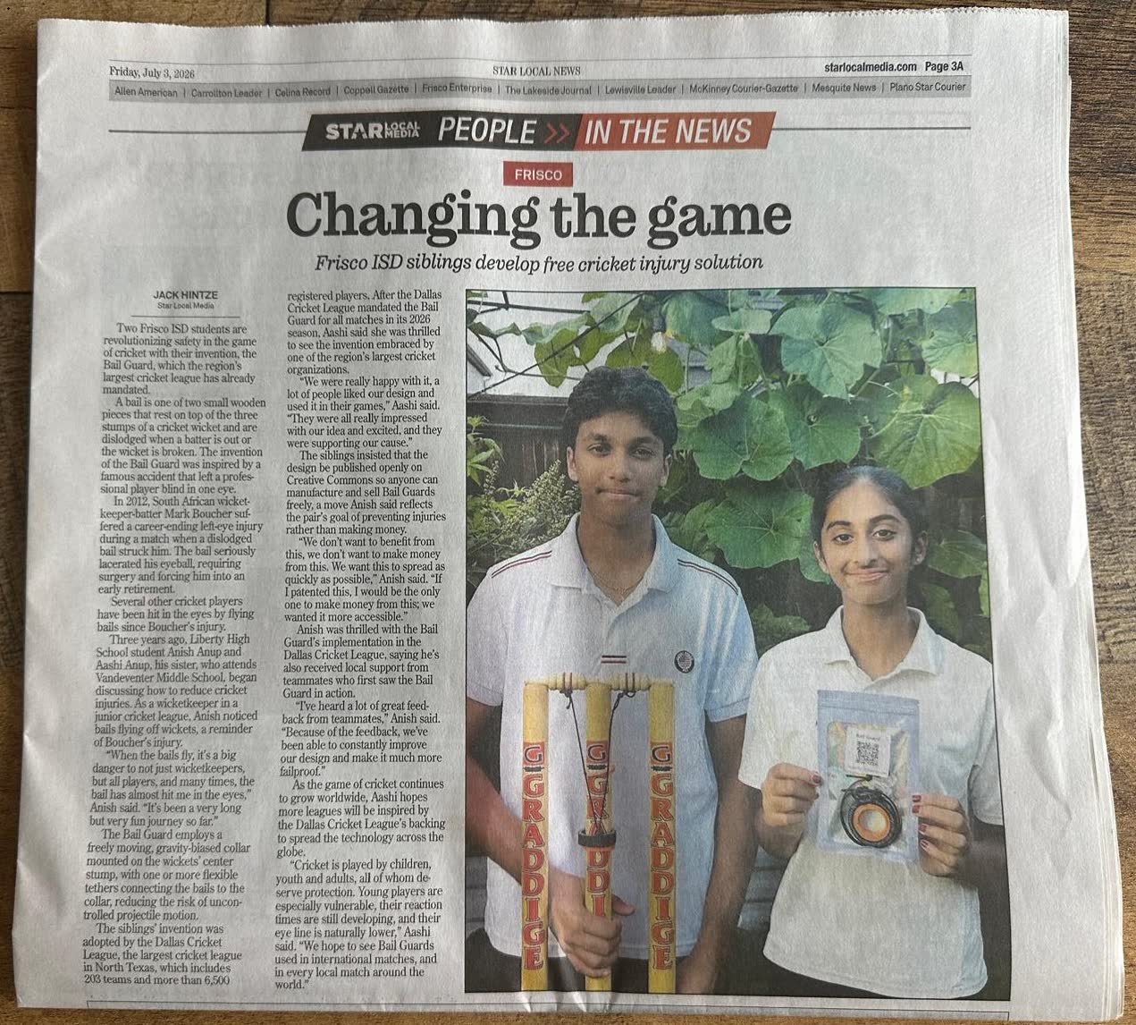A newspaper page headlined Changing the game, Frisco ISD siblings develop free cricket injury solution, with a photograph of Aashi and Anish Anup holding a set of stumps fitted with a bail guard and a packaged device.